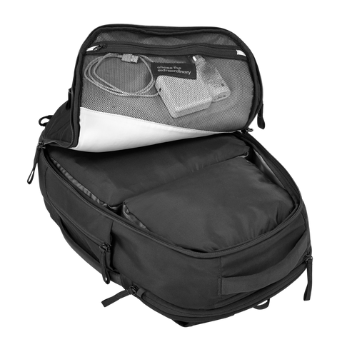 Black backpack with open front compartment showing electronic devices on a white background