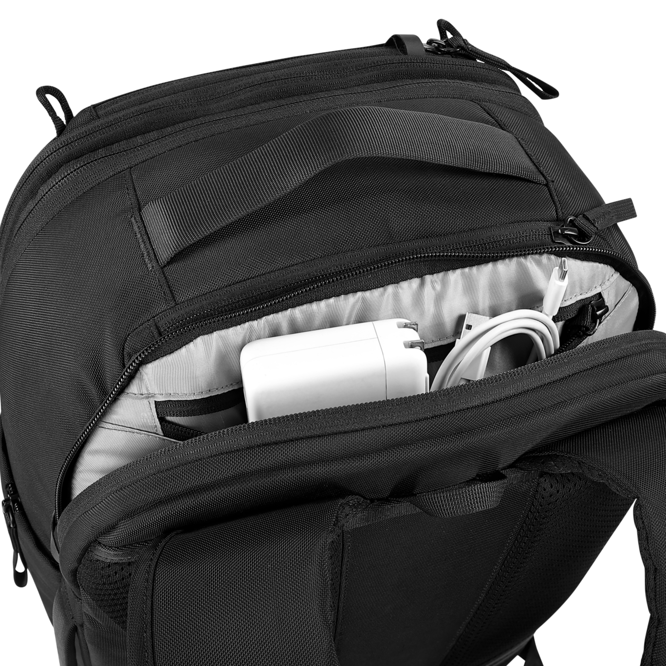 Black backpack with open compartment showing white electronic devices on a black background