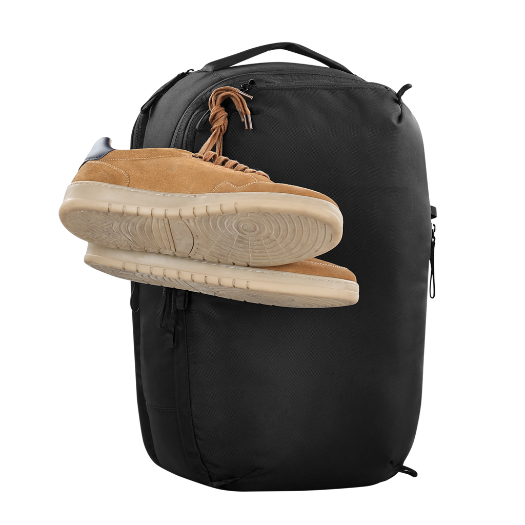 Black backpack with a tan sneaker on top against a white background
