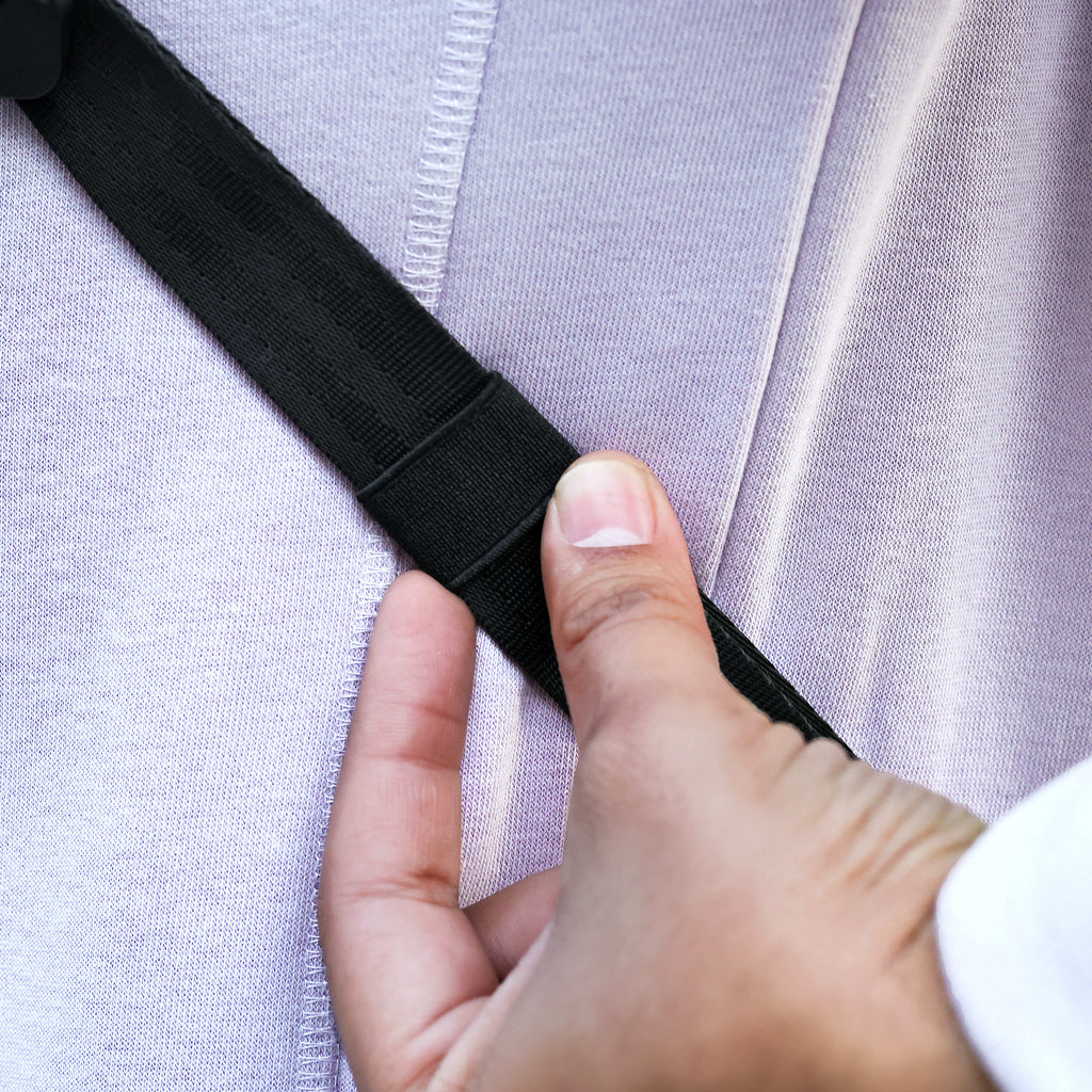 Hand adjusting a black strap on a light purple garment
