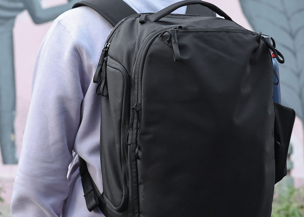 Black backpack worn by a person with a blurred background